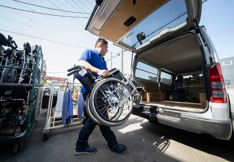 車いすを車両に積み込むスタッフの写真